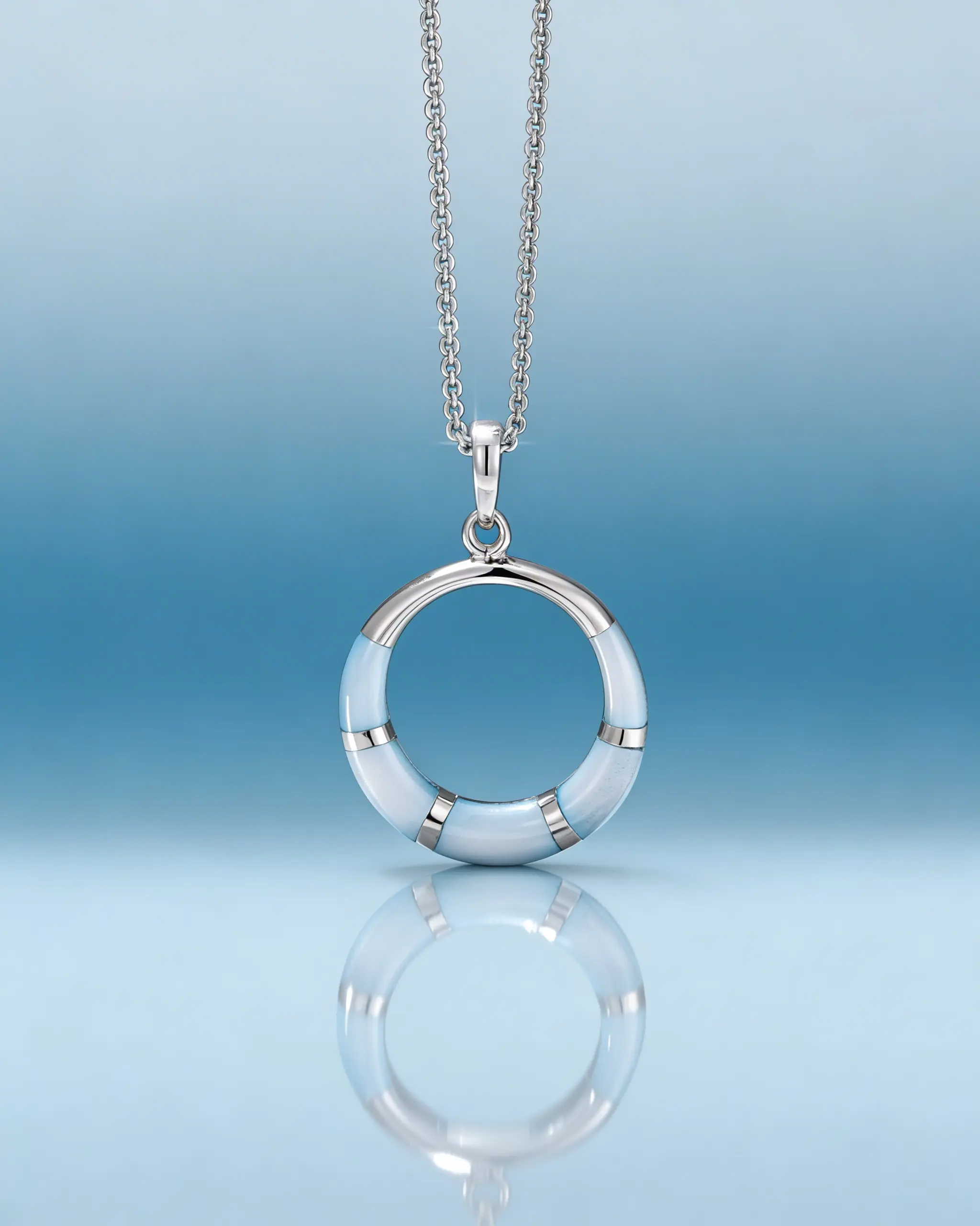 Серебряная подвеска в виде кольца на цепочке с отражением на голубом фоне.