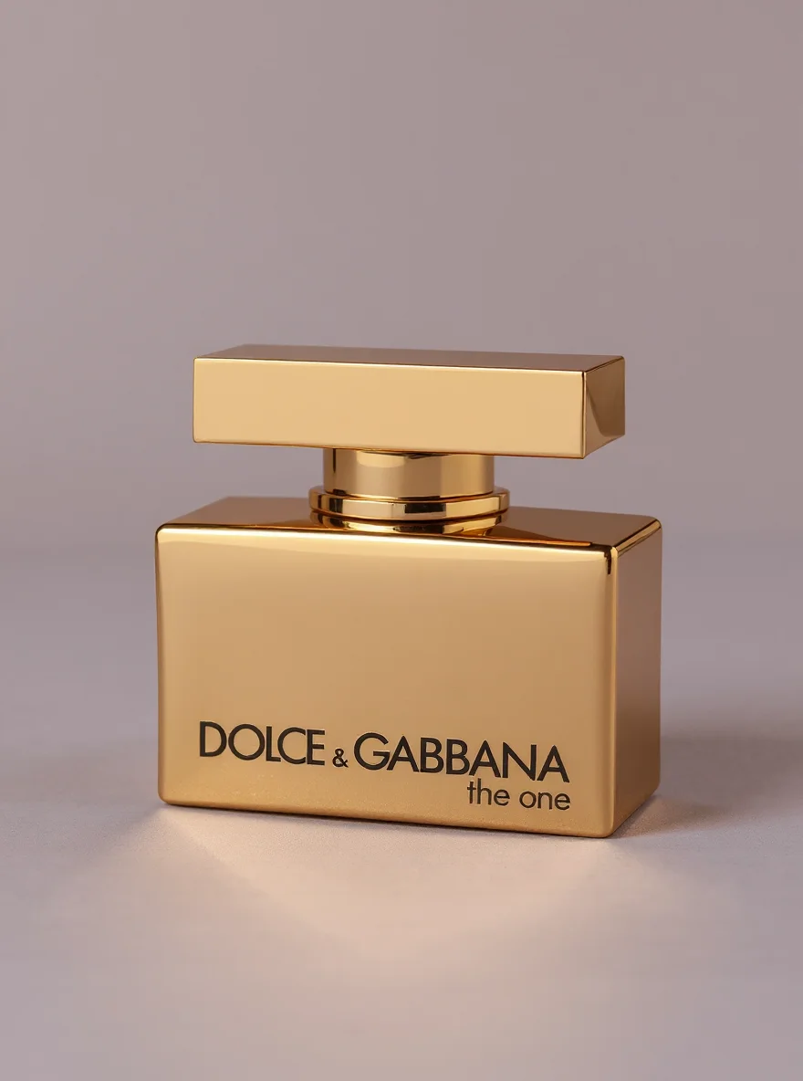 Золотой флакон духов Dolce & Gabbana на нейтральном фоне.